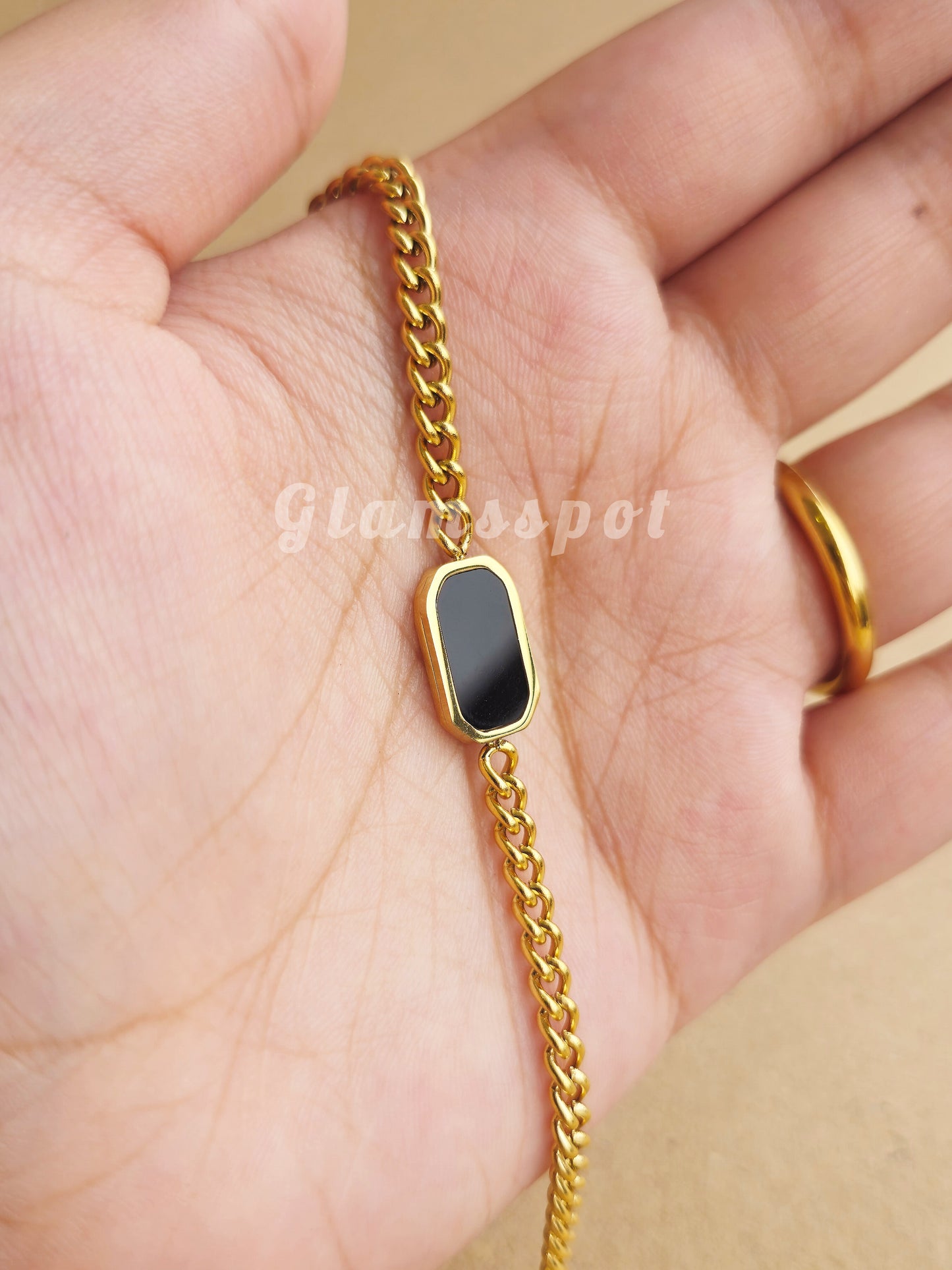 Gold Black Dial Bracelet with a black stone on a hand, brand 'glamsspot' visible