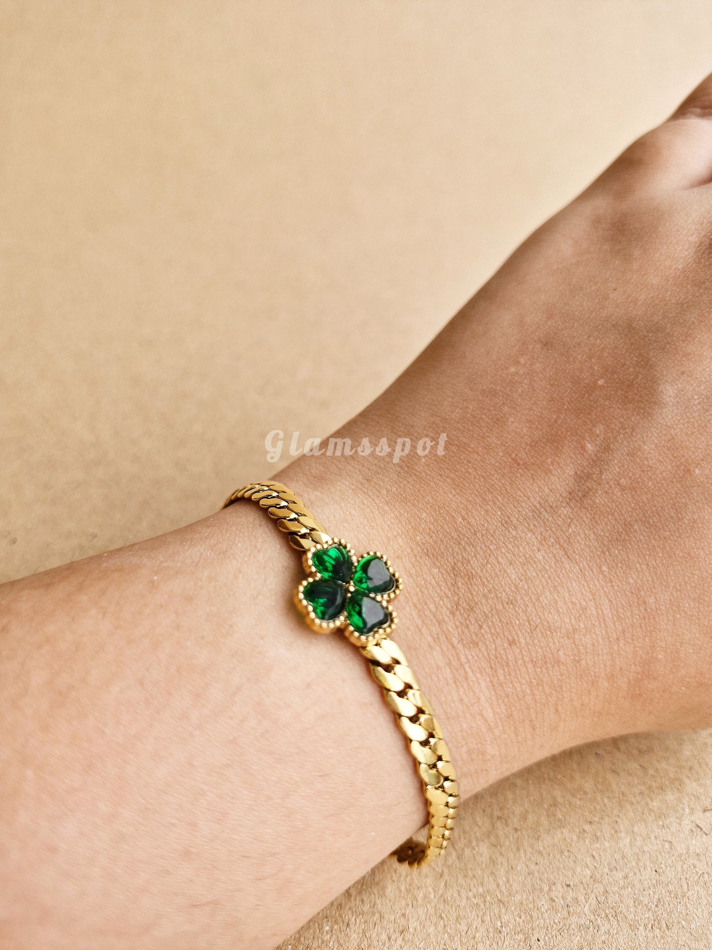 Emerald Green Bracelet with green gemstones on a wrist against a beige background