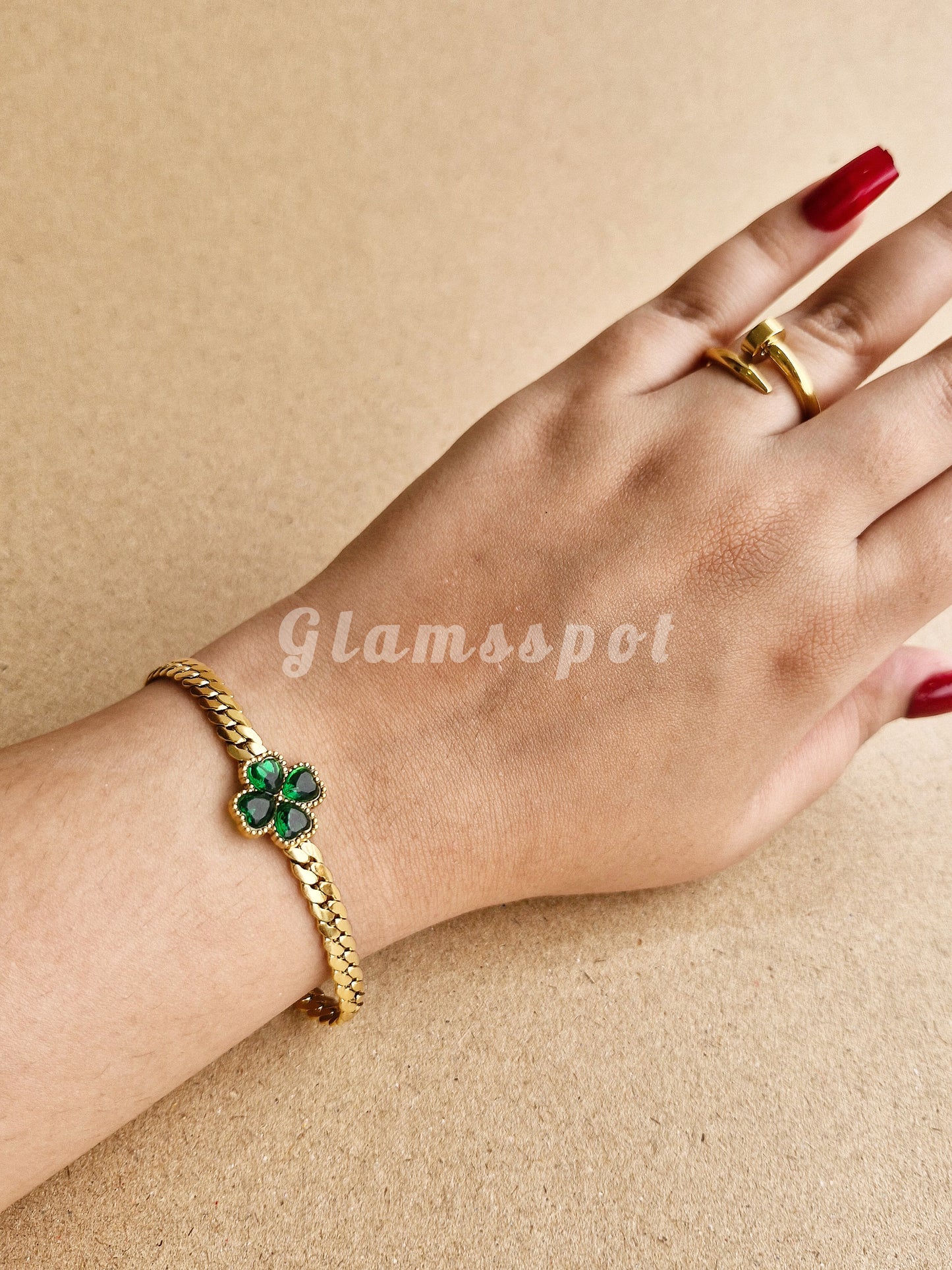 Emerald Green Bracelet with green gemstones on a hand against a beige background, featuring the brand 'Glamsspot'.