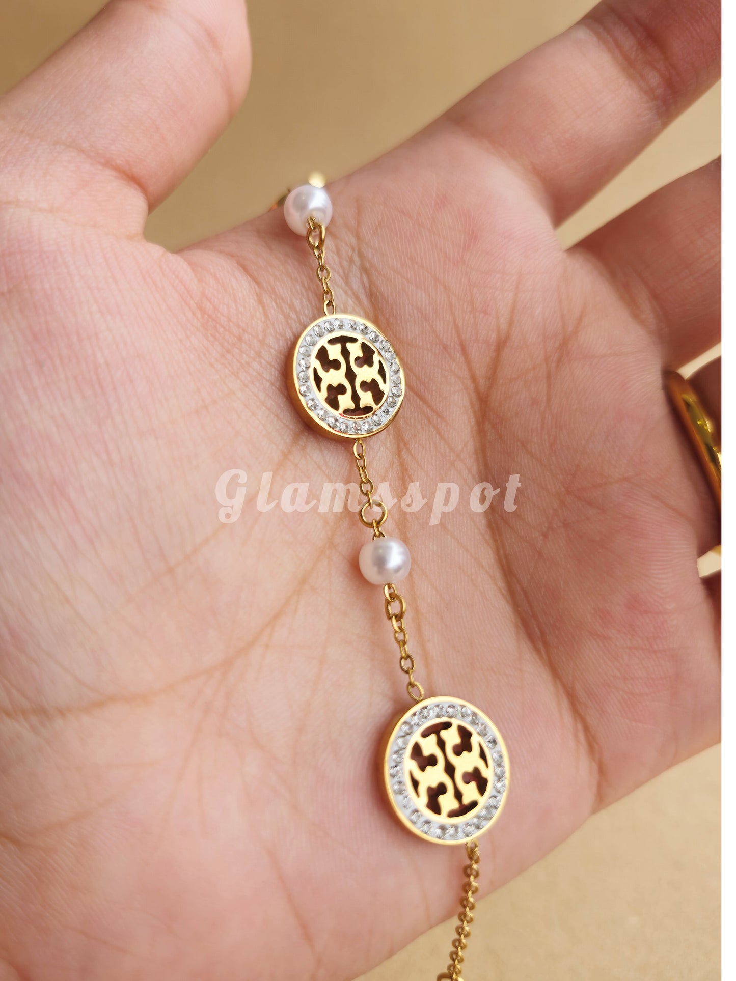 Gold Minimal Tory Bracelet with leopard print charms on a hand, brand 'Glamspot' visible