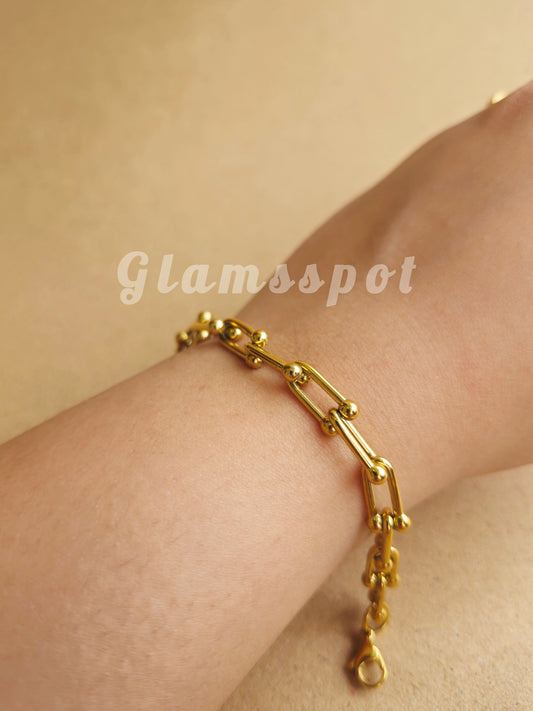 Gold chain bracelet on a wrist with a beige background, Tiffany and co inspired