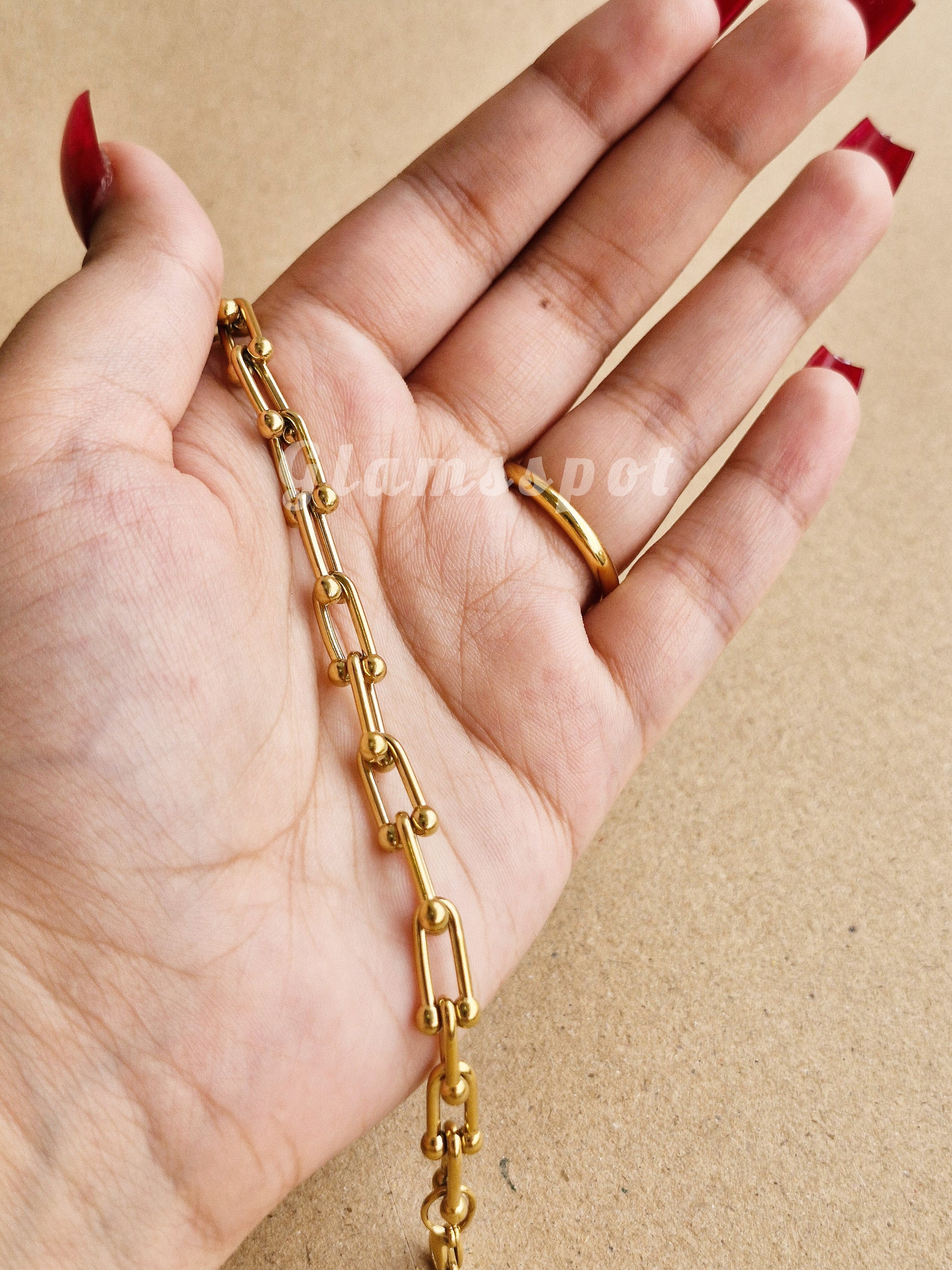 Gold chain held in a hand against a beige background, Tiffany and co inspired