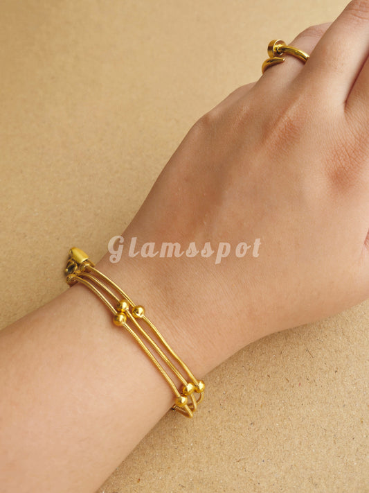 Gold 3 Layer Ball Bracelet and ring on a wrist against a beige background, with 'Glamsspot' branding.