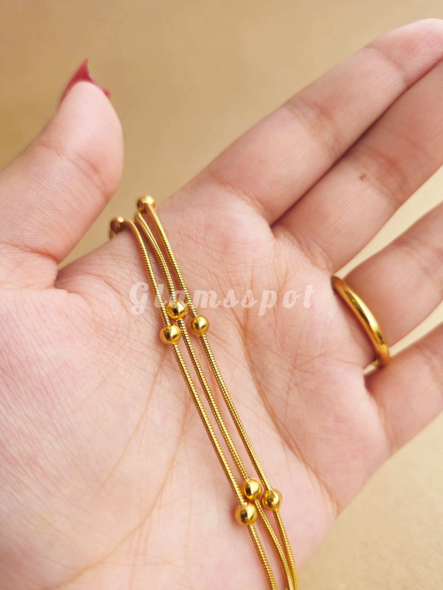 Gold bracelet on a hand with a plain background