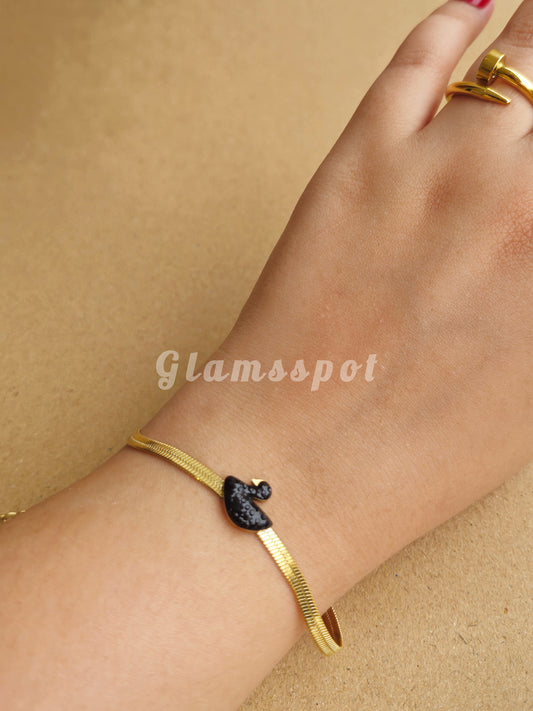 Gold Black Swan Bracelet on a wrist with a beige background, featuring the brand 'Glamsspot'.