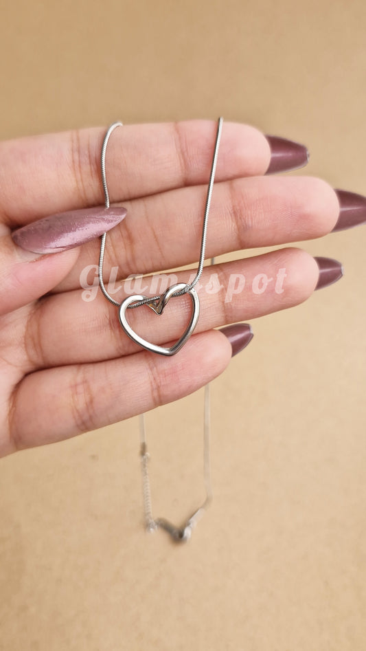Heart-shaped necklace held by a hand with a beige background