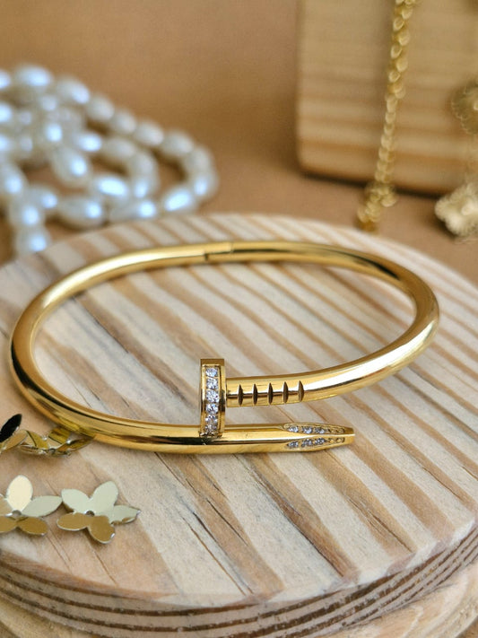Gold bracelet with a unique design on a wooden surface