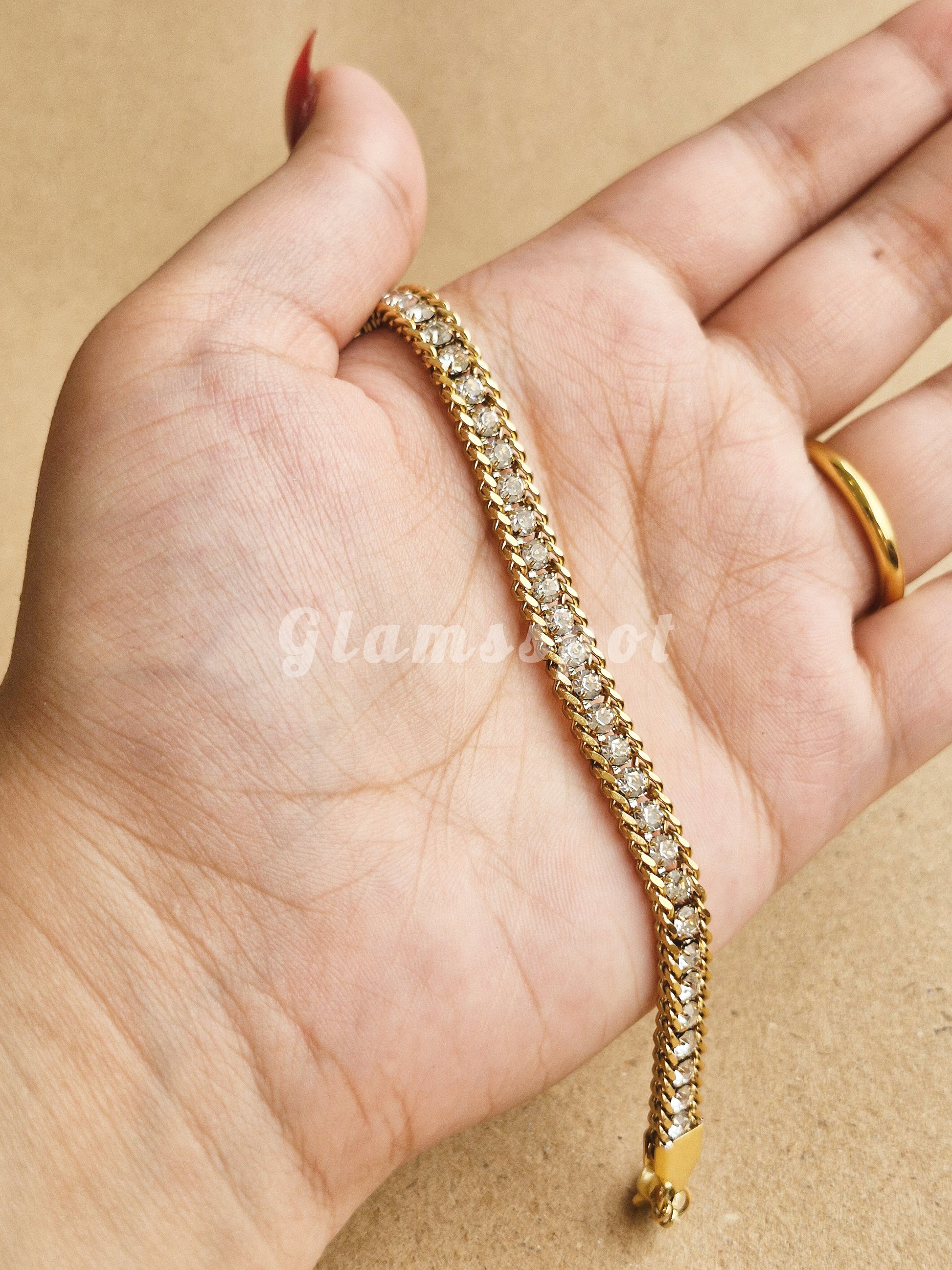 Gold Tennis Bracelet on a hand with a beige background