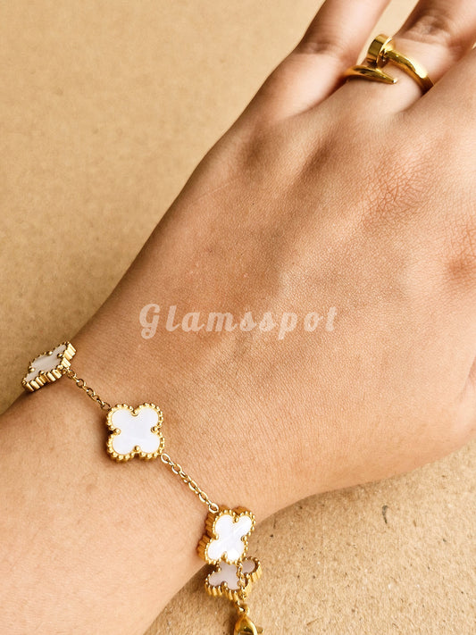 White Clover Bracelet with white stones on a wrist against a beige background, branded 'Glamsspot'.
