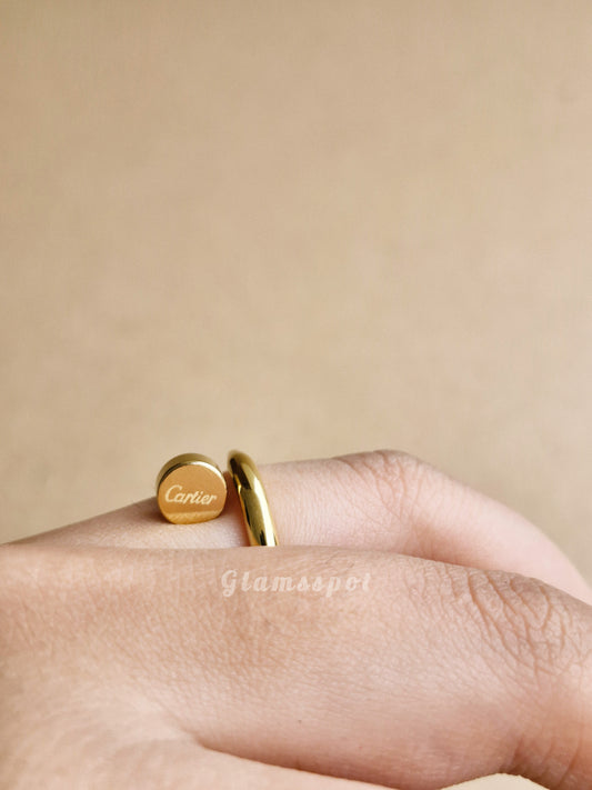 A human hand wearing a Cartier nail gold ring